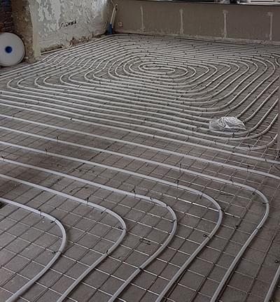 Vloerverwarming geheel geisoleerd met een purlaag met daarover beton. verwarmingsleidingen gemonteerd op een mat , hierover komt een afwerklaag en tegels 